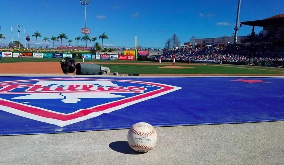 Baseball stadium with audience and logo on the field during game.