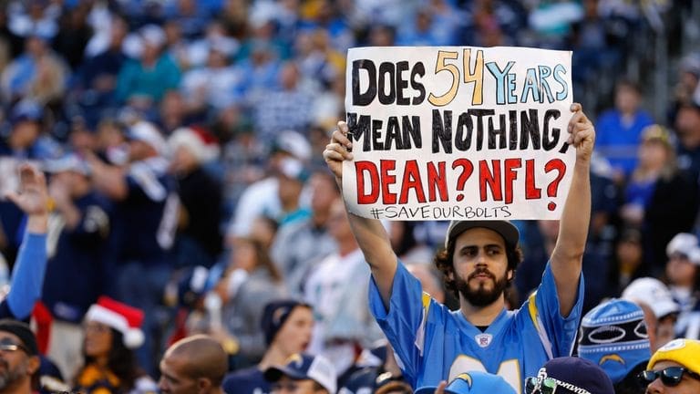 Protest fan holding sign at NFL game advocating for stadium subsidy funding.